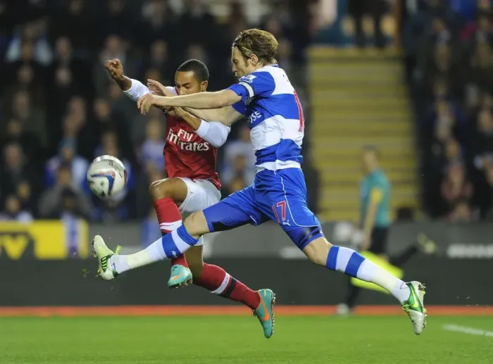 Framed Print : Theo Walcott vs Kaspars Gorkss: Intense Battle in Reading v Arsenal Capital One Cup Clash