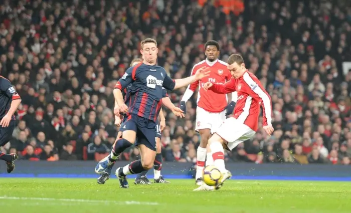 Framed Print : Thomas Vermaelen shoots past Bolton defender Gary Cahill to score the 3rd Arsenal goal