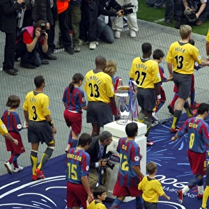 The Arsenal and Barcelona teams walk out past the European Cup