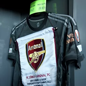 Arsenal FC Prepares for UEFA Europa League Clash against FC Zurich: Match Pennant and Captains Armband in the Changing Room