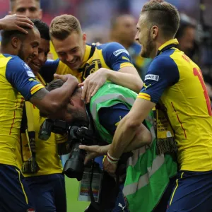 Arsenal photographer Stuart MacFarlane is grabbed by Aaron Ramsey and Theo Walcott after the match