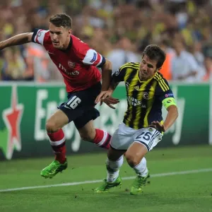 Arsenal's Aaron Ramsey Outmaneuvers Fenerbahce's Emre Belozoglu in UEFA Champions League Play-offs Clash
