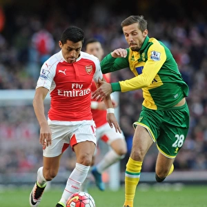 Arsenal's Alexis Sanchez vs. Norwich's Gary O'Neil: Intense Face-off during the 2015-16 Premier League Match