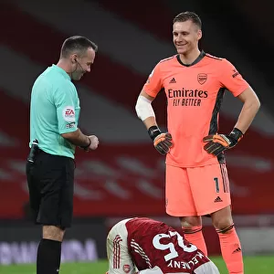 Arsenal's Bernd Leno Shares a Laugh with Referee Paul Tierney Amidst Mohamed Elneny Injury at Emirates Stadium