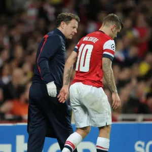 Arsenal's Jack Wilshere Receives Medical Attention from Physio Colin Lewin during UEFA Champions League Match against Borussia Dortmund (2013)