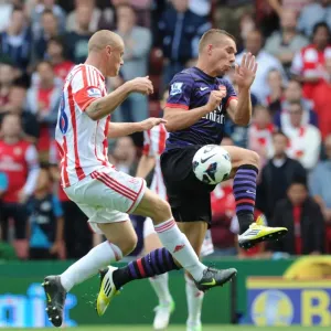 Arsenal's Lukas Podolski Faces Off Against Stoke City's Andy Wilkinson in 2012-13 Premier League Clash Arsenal's Lukas Podolski Faces Off Against Stoke City's Andy Wilkinson in 2012-13 Premier League Clash