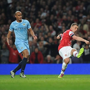 Arsenal's Lukas Podolski Outmaneuvers Manchester City's Vincent Kompany in the 2013/14 Premier League Clash