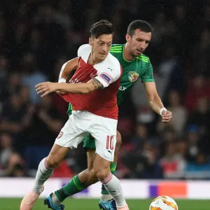 Arsenal's Mesut Ozil Clashes with Vyacheslav Sharpar of Vorskla Poltava in Europa League Match