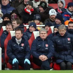 Arsenio Wenger el gerente del Arsenal se sienta en la banca con Pat Rice, asistente técnico.