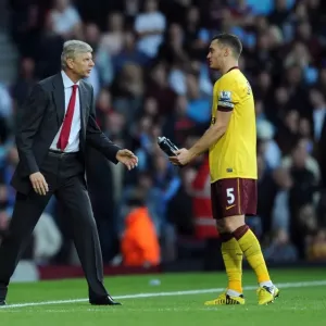 Arsene Wenger Conferring with Thomas Vermaelen during West Ham United vs Arsenal (2012-13) Arsene Wenger Conferring with Thomas Vermaelen during West Ham United vs Arsenal (2012-13)