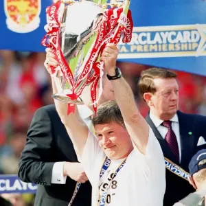 Assistant manager Pat Rice lifts the F. A. Barclaycard Premiership Trophy