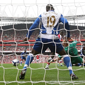 Emmanuel Eboue deflects the ball past Wigan goalkeeper