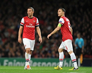 Arsenal FC vs Olympiacos FC: Lukas Podolski and Thomas Vermaelen in Action during the 2012-13 UEFA Champions League Match