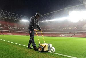 Images Dated 23rd December 2013: Arsenal Groundsman Sion Bennett Battles the Rain to Prepare for Arsenal vs. Chelsea Showdown