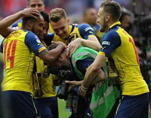 Arsenal photographer Stuart MacFarlane is grabbed by Aaron Ramsey and Theo Walcott after the match