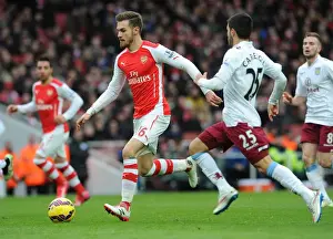 Arsenal V Aston Villa 2014-15 Prints: Arsenal's Aaron Ramsey Faces Off Against Aston Villa's Carles Gil in Intense Premier League Clash