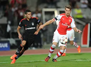 Besiktas V Arsenal 2014-15 Prints: Arsenal's Aaron Ramsey Faces Off Against Besiktas Ramon Motta in UEFA Champions League Qualifier