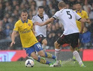 Images Dated 24th August 2013: Arsenal's Aaron Ramsey Outmaneuvers Fulham's Brede Hangeland in Premier League Clash