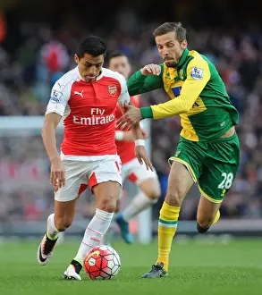 Arsenal's Alexis Sanchez vs. Norwich's Gary O'Neil: Intense Face-off during the 2015-16 Premier League Match