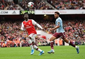 Arsenal v Aston Villa 2019-20 Collection: Arsenal's Bukayo Saka Faces Off Against Aston Villa's Trezeguet in Intense Premier League Clash