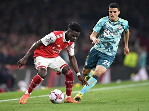 Images Dated 22nd April 2023: Arsenal's Bukayo Saka Fends Off Southampton's Mohamed Elyounoussi in Intense Premier League Clash
