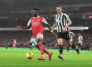 Arsenal V Newcastle United 2022-23 Prints: Arsenal's Bukayo Saka Goes Head-to-Head with Newcastle's Dan Burn in Premier League Battle