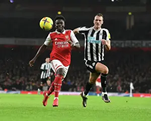 Arsenal V Newcastle United 2022-23 Prints: Arsenal's Bukayo Saka vs. Newcastle's Dan Burn: A Premier League Battle at Emirates Stadium