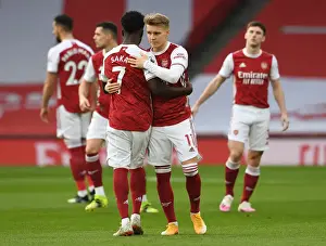 Arsenal's Embrace: Saka and Odegaard Unite Amidst Empty Emirates Stadium (Arsenal v Manchester City, 2021)