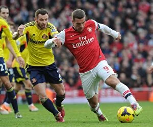 Arsenal v Sunderland 2013-14 Collection: Arsenal's Lukas Podolski Clashes with Sunderland's Phil Bardsley in Premier League Showdown