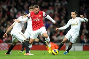 Arsenal v Swansea 2012-13 Collection: Arsenal's Lukas Podolski Fends Off Chico Flores and Leon Britton of Swansea during the 2012-13