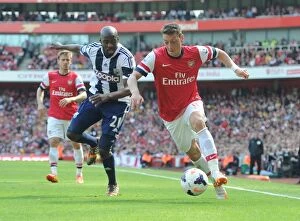 Arsenal v West Bromwich Albion 2013-14 Collection: Arsenal's Mesut Ozil Faces Off Against West Brom's Yossouf Mulumbu in 2013-14 Premier League Clash