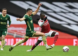 Arsenal's Nicolas Pepe Outmaneuvers Sheffield United's Jack Robinson in Empty Emirates Stadium