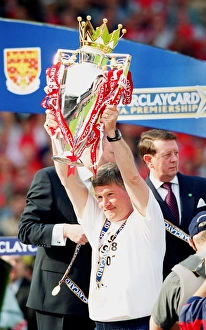 Assistant manager Pat Rice lifts the F. A. Barclaycard Premiership Trophy