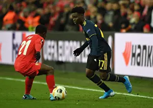 Standard Liege V Arsenal 2019-20 Prints: Bukayo Saka Faces Off Against Collins Fai in Arsenal's Europa League Clash with Standard Liege