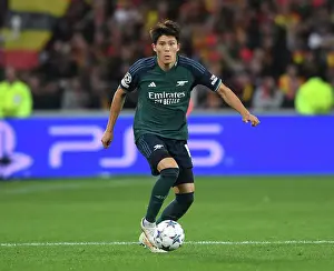 RC Lens V Arsenal 2023-24 Prints: Champions League 2023-24: Arsenal's Tomiyasu Faces Off Against RC Lens at Stade Bollaert-Delelis