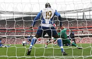 Emmanuel Eboue deflects the ball past Wigan goalkeeper