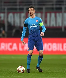 AC Milan V Arsenal 2017-18 Prints: Focused Koscielny: Arsenal's Defensive Hero in Europa League Battle at AC Milan