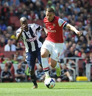 Images Dated 4th May 2014: Intense Battle: Lukas Podolski vs Youssouf Mulumbu - Arsenal v West Bromwich Albion, Premier League