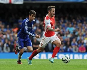 Chelsea v Arsenal 2014-15 Collection: Jack Wilshere vs. Oscar: Battle in the Heart of the Premier League Clash Between Chelsea