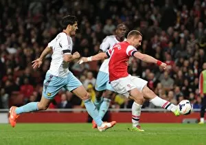 Images Dated 15th April 2014: Lukas Podolski scores his 2nd and Arsenals 3rd goal under pressure from James Tomkins (West Ham)