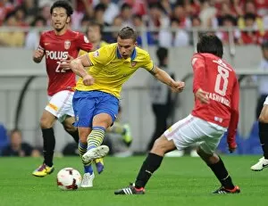 Uwara Red Diamonds v Arsenal 2013-14 Collection: Lukas Podolski vs. Yosuke Kashiwagi: A Battle for Ball Possession in Urawa Red Diamonds vs