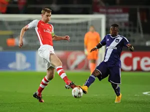 Anderlecht V Arsenal 2014-15 Prints: Per Mertesacker vs Cyriac: Intense Battle in Anderlecht v Arsenal UEFA Champions League Clash