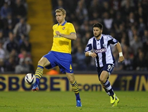 West Bromwich Albion V Arsenal 2013-14 - Capital Cup Prints: Per Mertesacker vs. Shane Long: A Battle for Control in the Capital One Cup (West Bromwich Albion vs)