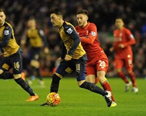 Images Dated 13th January 2016: Mesut Ozil Outmaneuvers Adam Lallana: Premier League Showdown between Liverpool and Arsenal