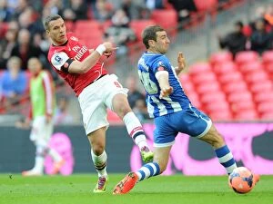 Images Dated 12th April 2014: Podolski vs McArthur: Intense Moment at the FA Cup Semi-Final between Arsenal and Wigan