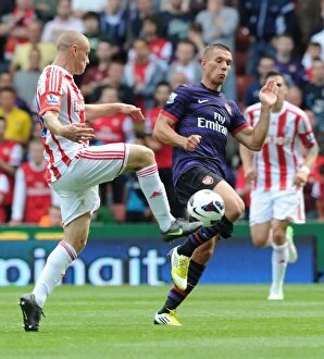 Images Dated 26th August 2012: Podolski vs. Wilkinson: Intense Clash in Stoke City vs. Arsenal (2012-13)