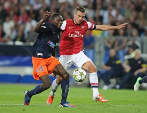 Montpellier V Arsenal 2012-13 Prints: Podolski vs Yanga-Mbiwa: Battle in the UEFA Champions League