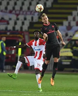 Red Star Belgrade V Arsenal 2017-18 Prints: Rob Holding Leaps Over Richmond Boakye in Europa League Clash between Crvena Zvezda and Arsenal