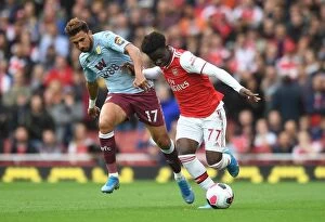 Arsenal v Aston Villa 2019-20 Collection: Saka vs Trezeguet: Intense Face-Off in Arsenal's Battle Against Aston Villa