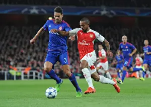 Arsenal V Olympiacos 2015/16 Prints: Theo Walcott vs. Alberto Botia: A Fierce Battle in Arsenal's 2015 Champions League Clash